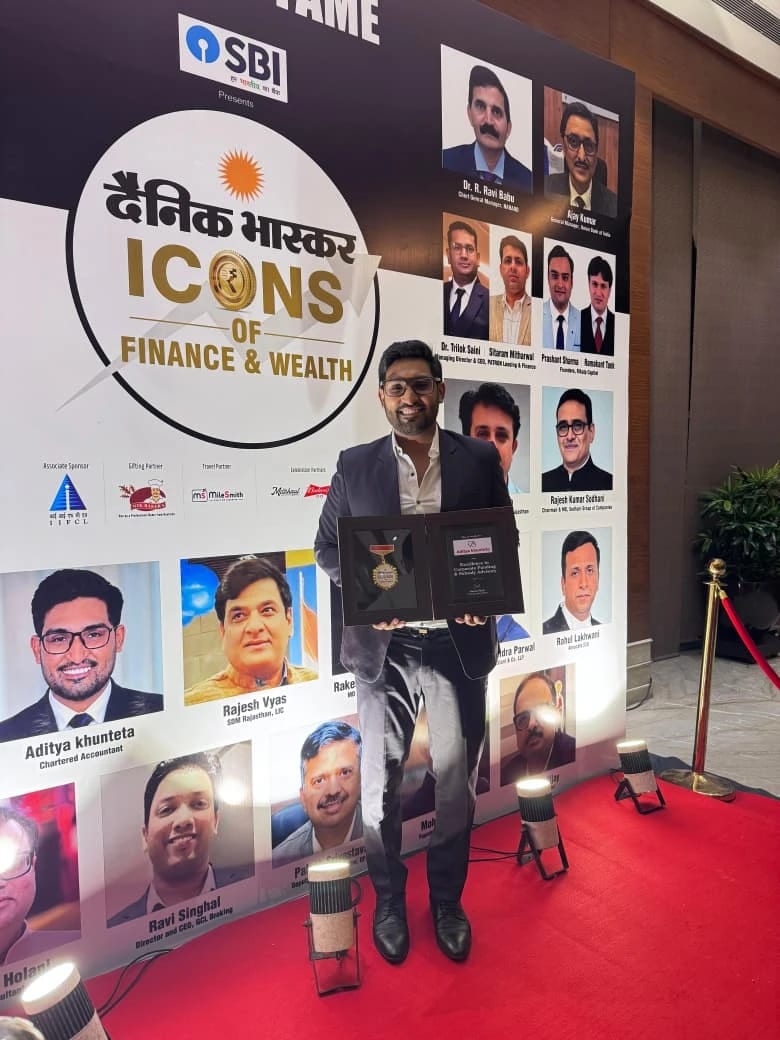 CA Aditya Khunteta holding his award in front of the Dainik Bhaskar Icons of Finance & Wealth Wall of Fame